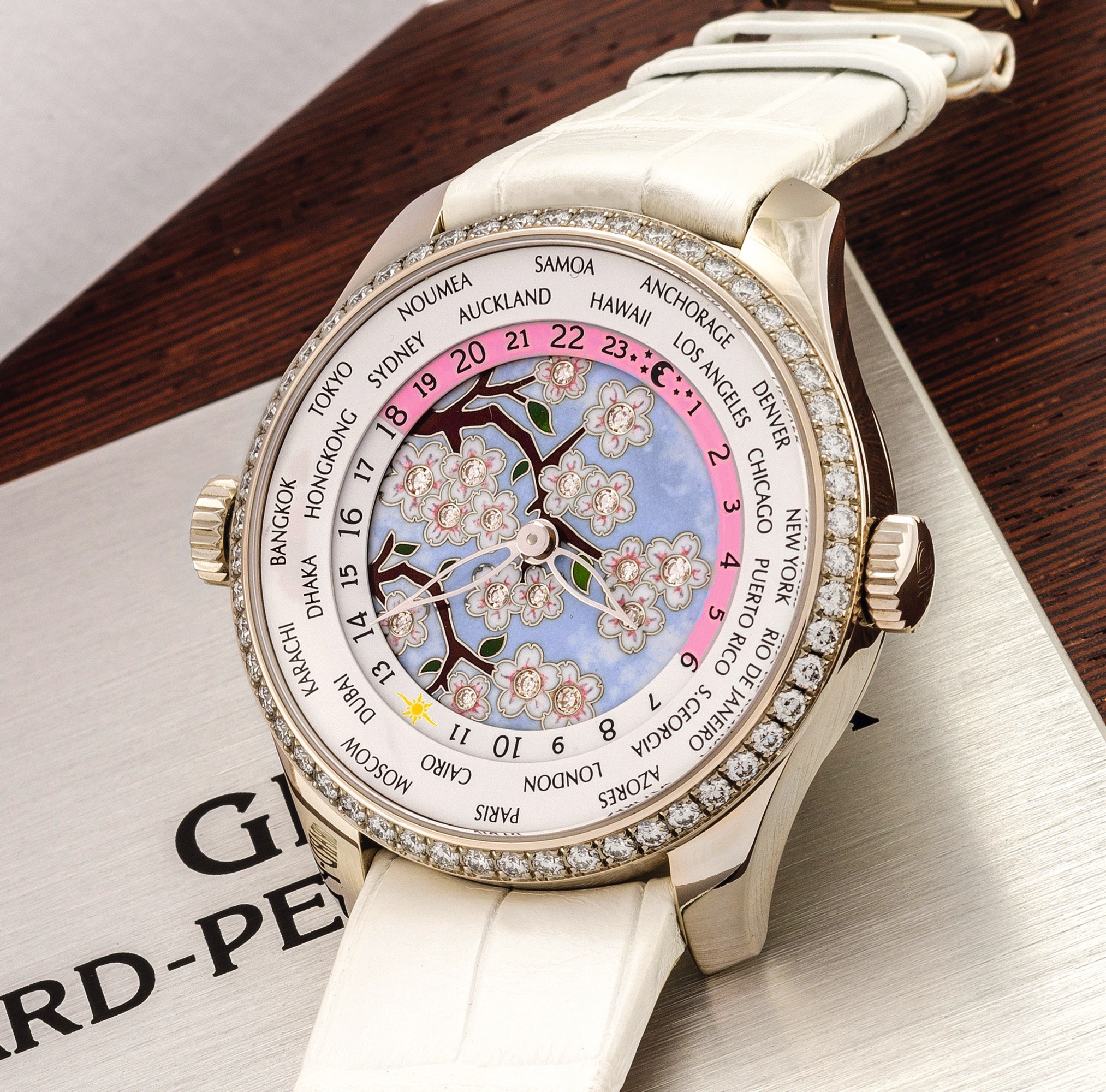 GIRARD-PERREGAUX REF. 49870 WORLD TIME ENAMEL
DIAMOND FLOWER DIAL DIAMOND BEZEL WHITE GOLD 
Girard-Perregaux, World Time, No. OG No. 2, Ref. 49870. Made circa 
2012. 
Very fine, large, world time, self-winding, diamond-set 18K white 
gold wristwatch with enamel diamond dial, two crowns, 24-hour 
day and night power reserve indication and an 18k white gold and 
diamond Girard Perregaux deployant clasp. Accompanied by the 
original fitted box, jewellery certificate and blank guarantee card