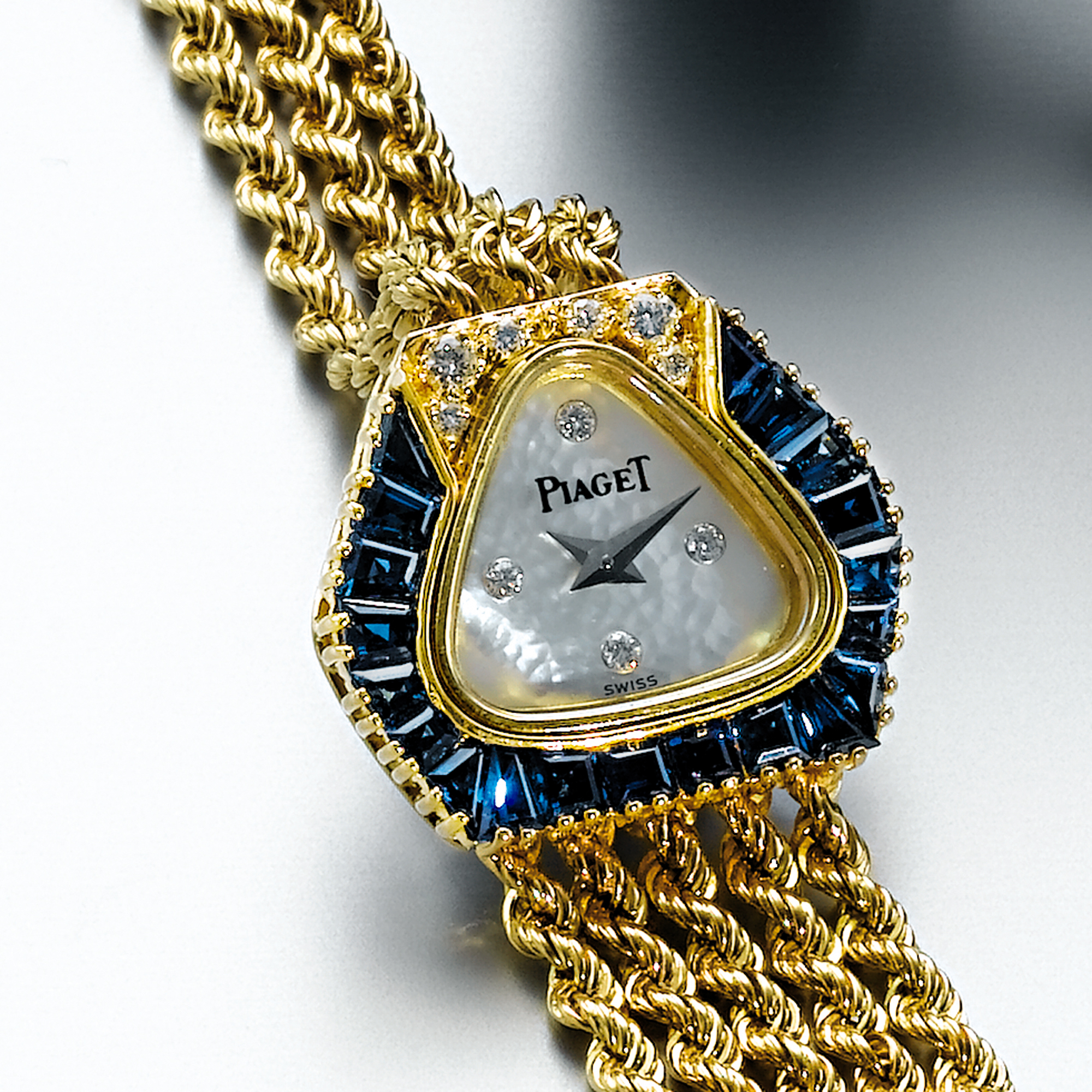 PIAGET, A LADY'S GOLD, SAPPHIRE AND DIAMOND SET WRISTWATCH WITH MOTHER-OF-PEARL DIAL CIRCA 1990