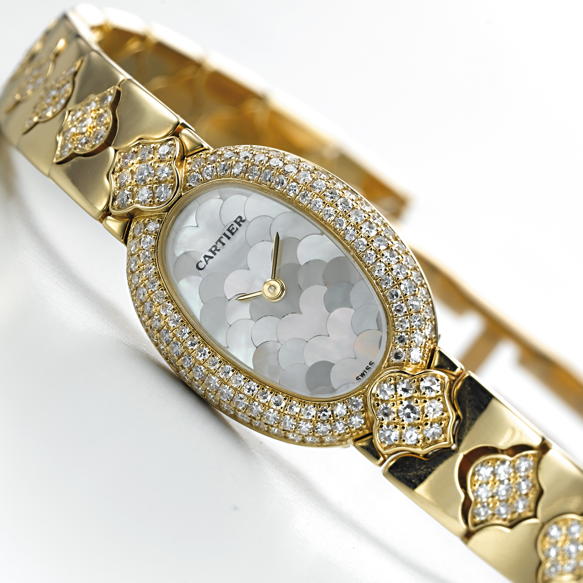 CARTIER, A LADY'S GOLD AND DIAMOND SET OVAL SHAPED BRACELET WATCH WITH MOTHER-OF-PEARL DIALMINI BAIGNOIRE, CIRCA 1995